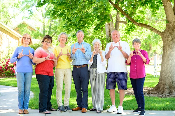 osher members smiling and flashing the U sign in a park